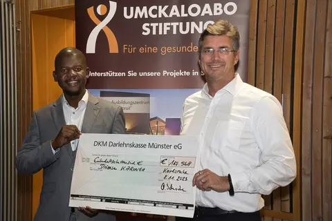 Olaf Schwabe, CEO of the Schwabe Group, presents Mwawi Shaba, the project manager for the St. Steven's School in Malawi, the donation from the Africa Runners."